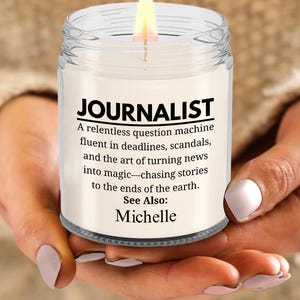 May include: A white candle with a clear glass jar and a black label that reads "JOURNALIST A relentless question machine fluent in deadlines, scandals, and the art of turning news into magic-chasing stories to the ends of the earth. See Also: Michelle"