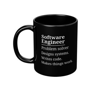 May include: A black ceramic mug with a white handle. The mug features the text "Software Engineer" above a list of job duties in white, including "Problem solver" and "Writes code."