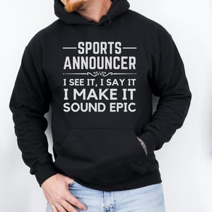 May include: Black hooded sweatshirt with white text that reads "Sports Announcer I see it, I say it I make it sound epic".