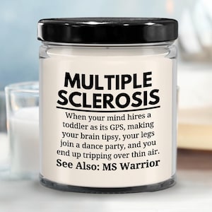 May include: White candle with a black lid and a black label that reads "MULTIPLE SCLEROSIS" and a humorous description of the condition. The label also says "See Also: MS Warrior".