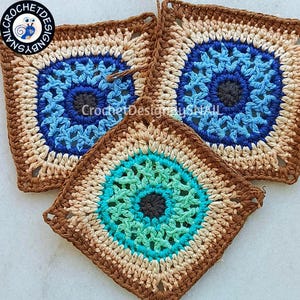 May include: Three handmade crochet squares with a central eye design. The squares feature concentric circles of blue, teal, and brown, surrounded by a tan and brown border. The text "Crochet Designs by Snail" is visible in the image.