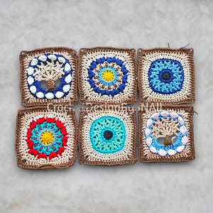 May include: Six crocheted squares with detailed patterns. Each square has a central design in colours like blue, yellow, red, and turquoise, framed by a brown border. The squares are arranged in a grid formation.