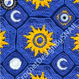 Puede incluir: Primer plano de una manta de ganchillo con un diseño celestial. La manta presenta formas geométricas azules, amarillas y blancas, incluyendo soles, lunas y estrellas. El texto "Crochet Design By Snail" es visible.