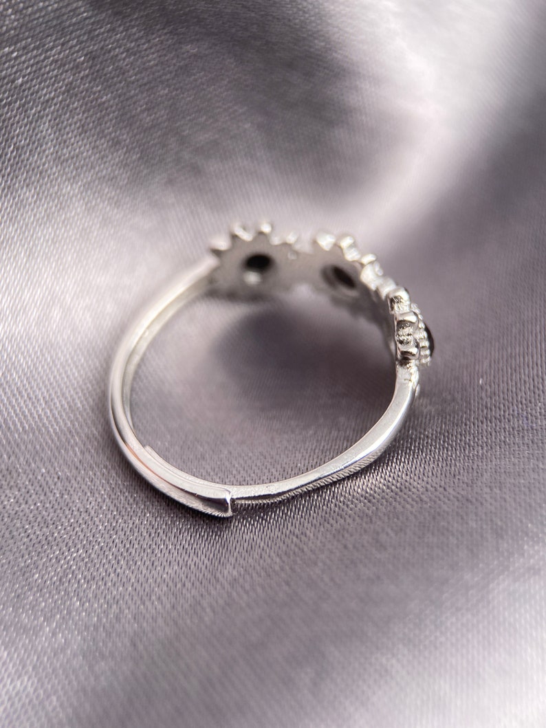 May include: Silver ring with a delicate design of small, round stones set in a floral pattern.