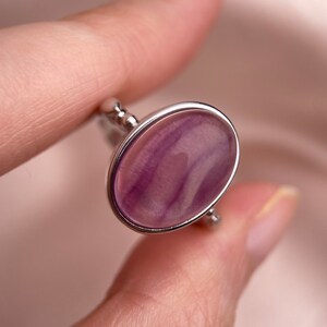 May include: A silver ring with a purple and white oval-shaped stone.