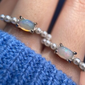 May include: Two silver rings with white opal stones set in a silver bezel. The rings are made of small white pearls.