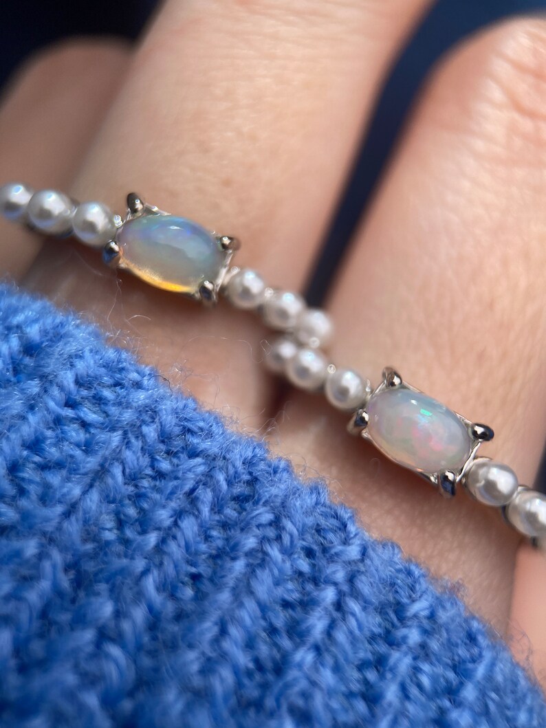 May include: Two silver rings with white opal stones set in a silver bezel. The rings are made of small white pearls.