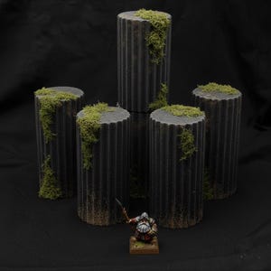 May include: Five gray, fluted miniature columns with green moss accents. A miniature figurine of a warrior stands in front of the columns. The columns are cylindrical and have a weathered appearance, suitable for tabletop gaming or model scenery.