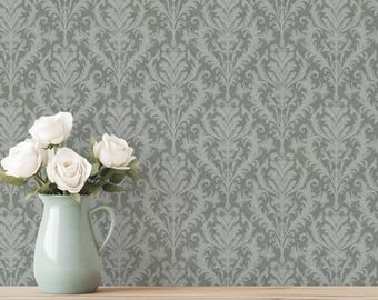 May include: A light green ceramic pitcher vase holds a bouquet of white roses. The vase features a curved handle and a wide base, while the roses have layered petals. The background displays a gray wallpaper with a repeating damask pattern.