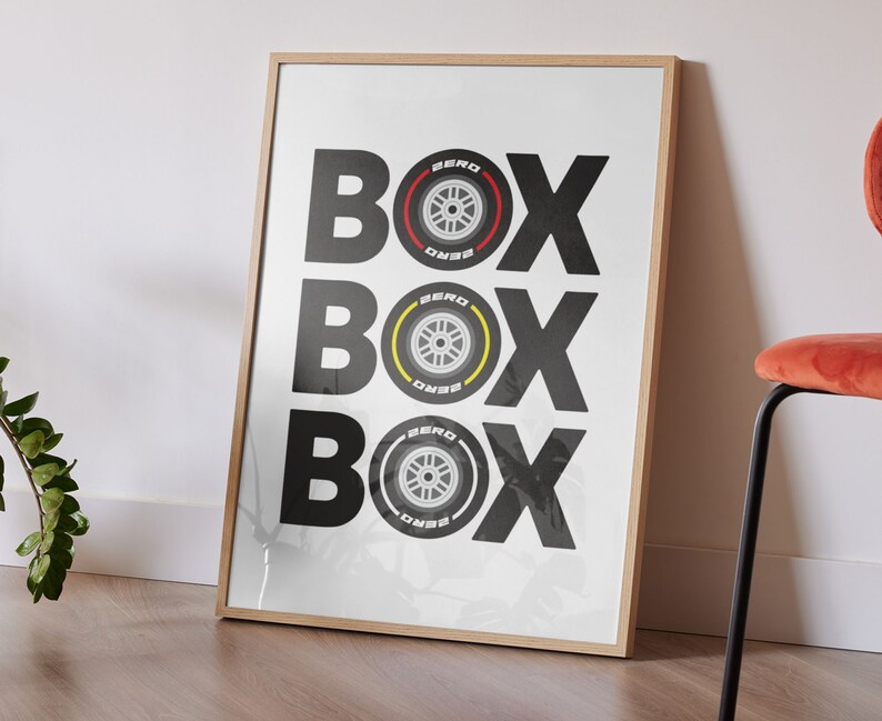 May include: A framed print with the word "BOX" repeated three times in black text. Each "BOX" has a black and white tire with red and yellow accents in the center.