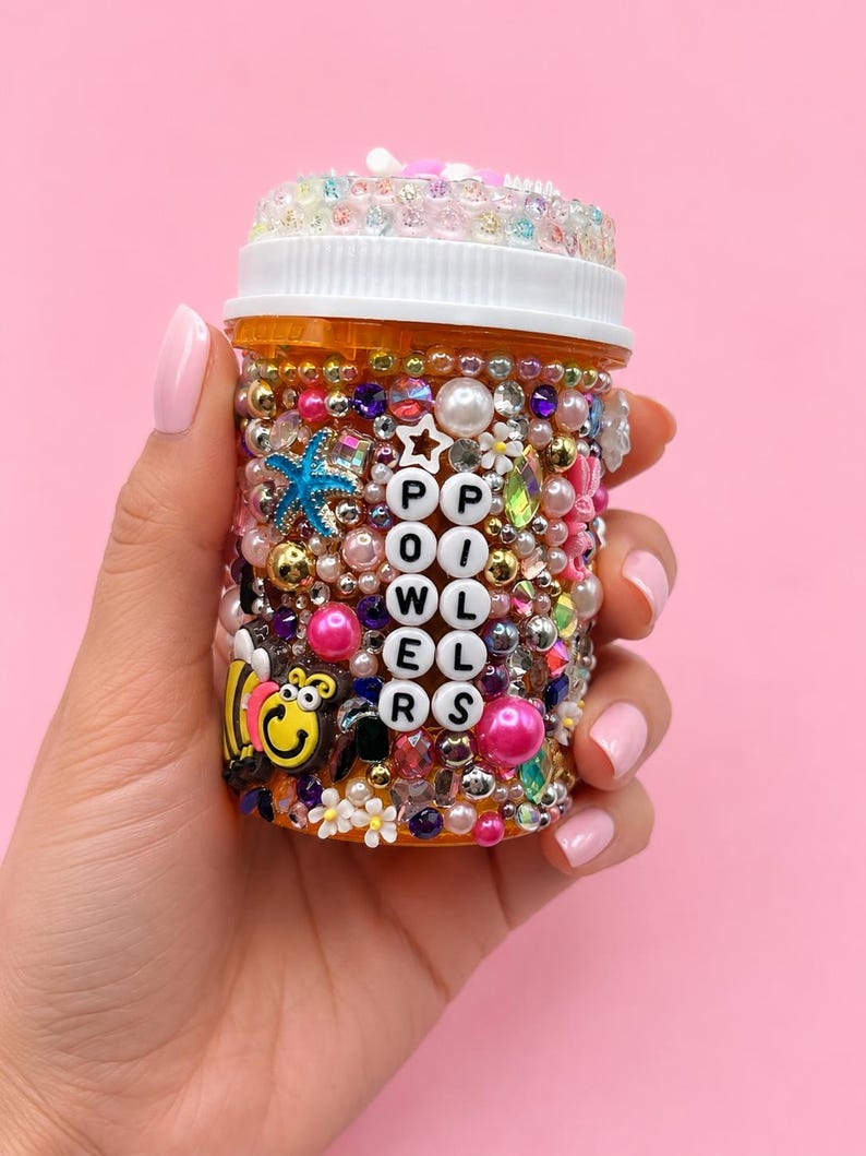 Orange pill bottle decorated with colorful beads, rhinestones, pearls, a starfish, and a bee charm, reading Power Pills