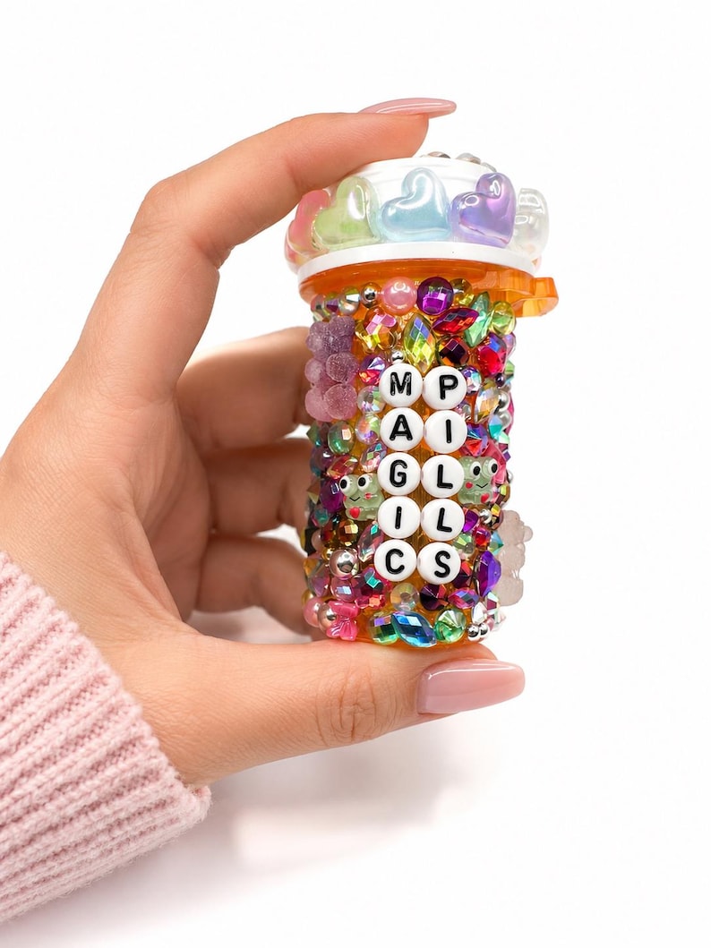 Rhinestone pill bottle covered in colorful gems, beads, and charms, reading MAGIC PILLS