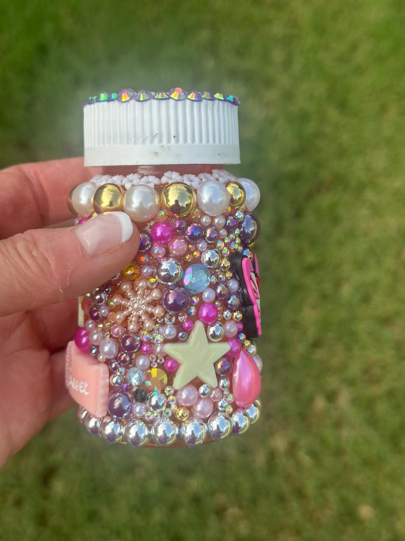 Hand-decorated breast cancer pill bottle with rhinestones, pearls, and charms