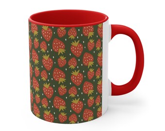 May include: A white ceramic mug with a red rim and handle. The mug features a repeating pattern of red strawberries on a dark green background.