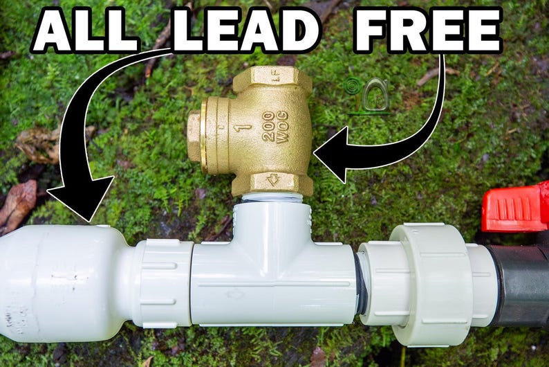 May include: A plumbing assembly featuring a brass valve and white PVC pipes, with the text "ALL LEAD FREE" in a bold, white font. The assembly includes a red valve handle and is set against a backdrop of green foliage.