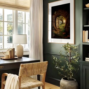 May include: A home office with a dark green wall, a wooden desk, a woven chair, a white lamp, and a framed print of a door in a tree. The print is in a dark brown frame and is hanging on the wall. There is a small potted plant in the corner of the room.