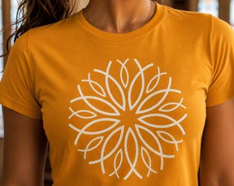 May include: A mustard yellow short-sleeved t-shirt featuring a large, white, symmetrical circular graphic on the chest. The design consists of multiple overlapping, curved, leaf-like shapes arranged in a radial pattern, creating a floral-like motif.