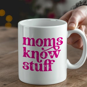 May include: White ceramic coffee mug with a pink design that says "moms know stuff".
