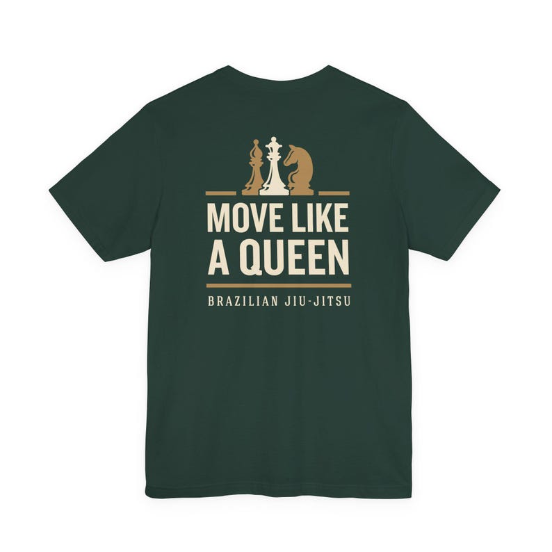 May include: A dark green short-sleeve t-shirt featuring a graphic on the back. The design includes three chess pieces above the text MOVE LIKE A QUEEN and the words BRAZILIAN JIU-JITSU in a light cream color, centered on the upper back area.