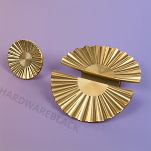 May include: Two gold-toned cabinet knobs with a sunburst design. The larger knob is a half-circle shape and the smaller knob is a circle.