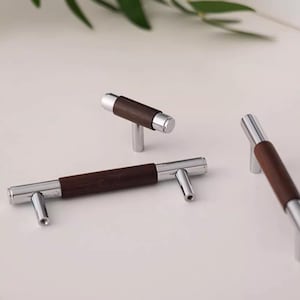 May include: Three cabinet pulls with a chrome finish and a dark wood insert. The pulls are in different sizes.