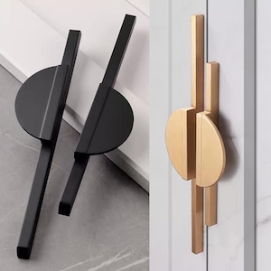 May include: Two black and one gold cabinet door handles with a modern geometric design. The handles are made of metal and have a sleek, minimalist look.