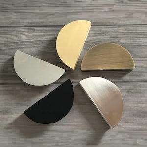 May include: Five half-circle cabinet pulls in different finishes: gold, brass, silver, brushed nickel, and black.
