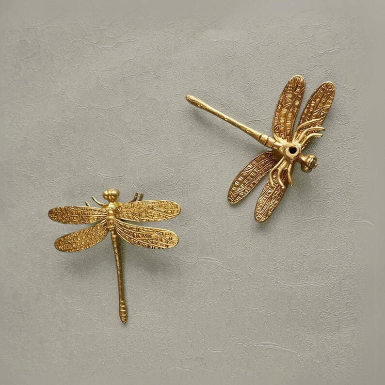 Puede incluir: Dos piezas de decoraci&oacute;n de pared de lib&eacute;lula de metal dorado. Las lib&eacute;lulas tienen detalles intrincados y son una gran adici&oacute;n a cualquier decoraci&oacute;n del hogar.