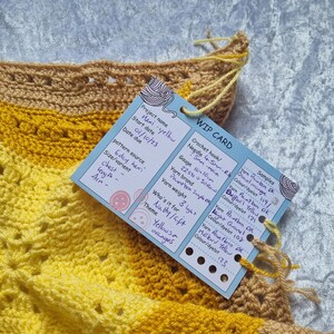 May include: A crocheted item in yellow and tan hues, with a WIP card attached. The card details the project name "Hexi-yellow", start date, and yarn specifics. The theme is "Yellows & oranges". The gauge is 10x10cm.
