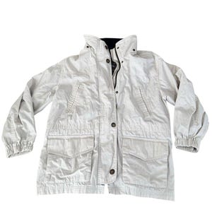 May include: A light beige utility jacket featuring a high collar, a front zipper closure concealed by a buttoned placket, two large flap pockets at the waist, two slanted chest pockets, and elasticized cuffs on the long sleeves.
