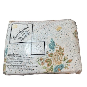 May include: A 3-piece twin sheet set by Lady Pepperell in no-iron muslin. The fabric features a floral pattern with orange, yellow, and blue flowers on a white background. The packaging lists dimensions for a flat sheet, fitted sheet, and pillowcase.