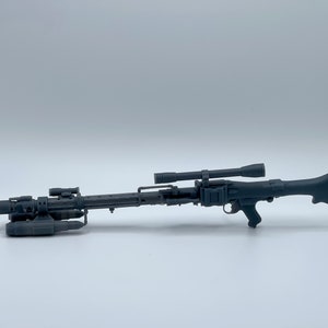 May include: A gray, detailed replica of a blaster rifle, featuring a scope, handle, and various attachments. The weapon is a prop or model, likely for display or cosplay purposes. The design is reminiscent of science fiction weaponry.