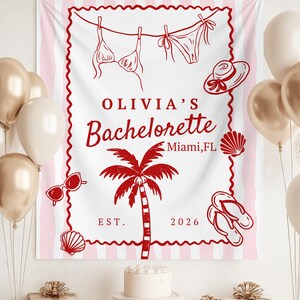May include: A white and pink striped banner with red line art of a bikini, hat, sunglasses, seashells, palm tree, and flip-flops. The banner reads "OLIVIA'S Bachelorette Miami, FL EST. 2026". Gold and white balloons and wrapped gifts are in the background.