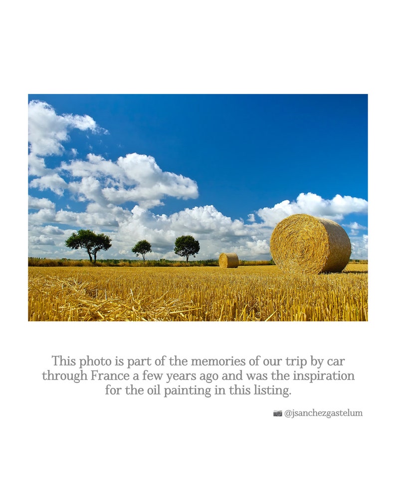 May include: A field of golden wheat with three trees and three round hay bales. The sky is blue with white clouds.