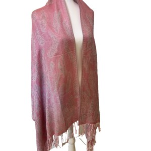 May include: A pink shawl with a white paisley pattern and fringe trim.