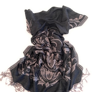 May include: A black and grey patterned scarf with fringe. The scarf has a floral design.