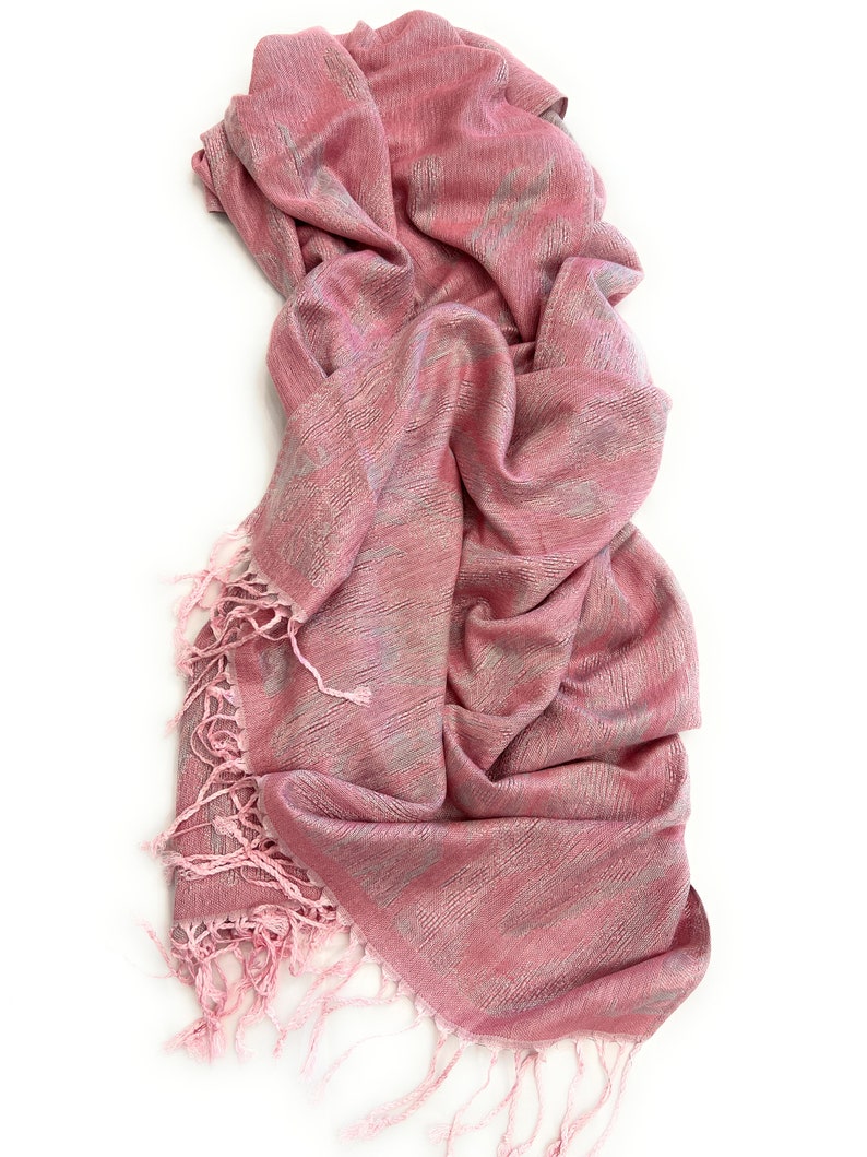 May include: A pink and silver patterned scarf with fringe on the ends.