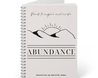 May include: A gray spiral bound journal with the words "Words to inspire and invoke" and "Abundance" in black text. The journal has a black and white illustration of a sun rising over mountains. The text "Manifestation and Meditation Journal" is printed at the bottom.