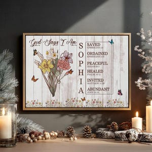 May include: A rectangular wall art print in a wooden frame featuring a bouquet of yellow and pink flowers, butterflies, and the text God Says I Am Sophia with a list of spiritual affirmations including Saved, Ordained, Peaceful, Healed, Invited, and Abundant.