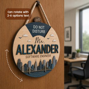 May include: A circular wooden door sign featuring a rope hanger, displaying the text DO NOT DISTURB, Mr. ALEXANDER, and SOFTWARE ENGINEER. The design includes a layered city skyline, a bridge, and clouds in shades of blue, gray, and natural wood.