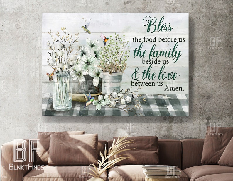 May include: A white wood sign with a green checkered background and a floral arrangement. The sign has a green inscription that reads "Bless the food before us the family beside us & the love between us Amen."