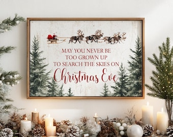May include: A rectangular framed wall art print featuring a watercolour illustration of Santa in a sleigh pulled by reindeer. The text reads: MAY YOU NEVER BE TOO GROWN UP TO SEARCH THE SKIES ON Christmas Eve. The background is a textured off-white.