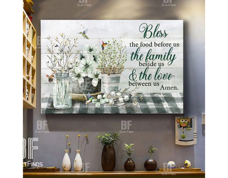May include: A white wood sign with a green checkered background and a floral arrangement in mason jars. The sign reads "Bless the food before us the family beside us & the love between us Amen."