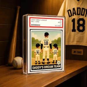 May include: A framed baseball card featuring a family illustration. The card reads "2025 Family League No. 1 Dad" and "Daddy's Dream Team." The illustration depicts a father and two children in baseball uniforms. A baseball bat, ball, and jersey are in the background.