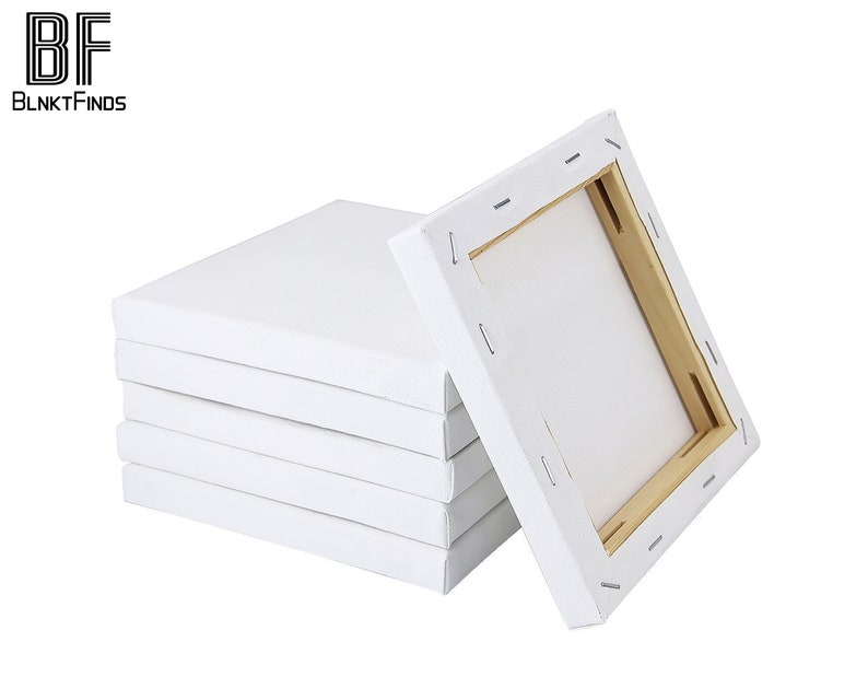 May include: A stack of five white canvas panels with wooden frames. The panels are all the same size and are stacked on top of each other. The top panel is slightly angled to the right.