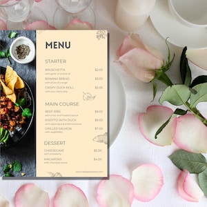 以下が含まれることがあります： 薄い黄色の背景と花柄のデザインのメニュー。メニューは、前菜、メインコース、デザートの選択肢と価格を記載しています。メニューは、ピンクのバラの花びらが散りばめられた白いテーブルクロスの上に置かれています。