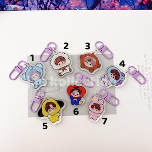 May include: A collection of seven acrylic keychains with cartoon character designs. Each keychain features a different character in various colors, with a purple clasp. The keychains are numbered 1 through 7.