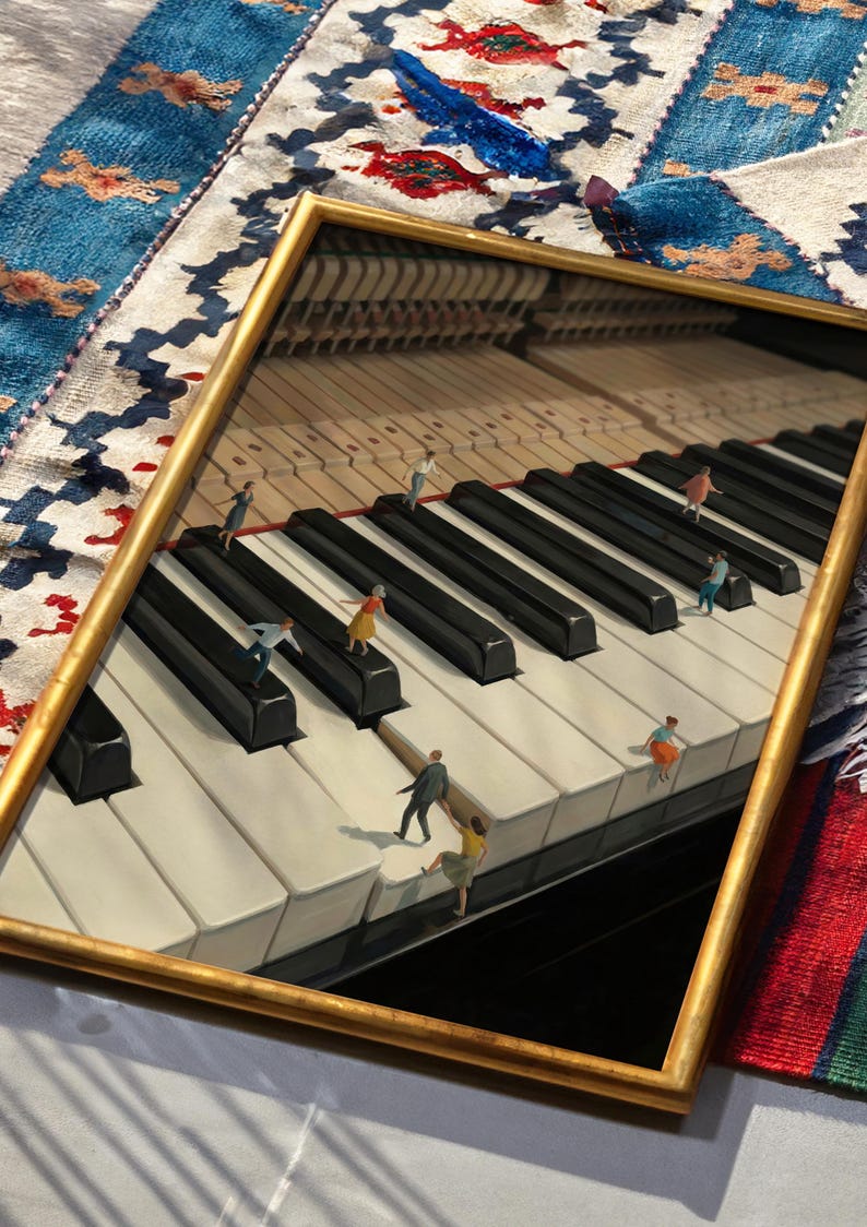 May include: A framed artwork depicts a piano keyboard with miniature figures interacting on the keys. The gold frame surrounds the image, which features black and white keys and a detailed interior. The background includes a colorful rug.