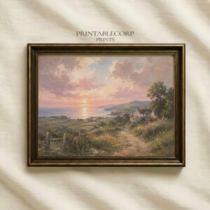 Peut inclure: Une peinture de paysage dans un cadre marron foncé représentant une scène côtière au coucher du soleil avec un ciel rose et orange, un océan calme, des collines verdoyantes, un chemin de terre et une petite maison parmi les arbres. Le texte PRINTABLECORP PRINTS est visible.