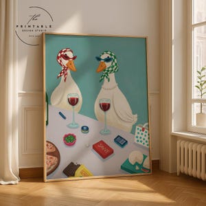 May include: A framed art print showing two geese wearing sunglasses and scarves, enjoying wine and snacks. The geese are at a table with food and drinks, with the word "SAVVY" on a red box. The background is a light teal colour.
